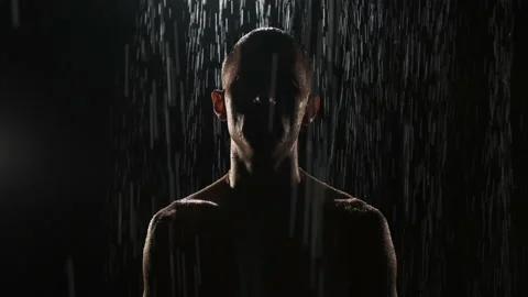 Portrait of pumped-up guy at night in the rain on black background. Close-up of Stock Footage 139726229