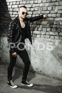 Portrait of a punk man near a brick wall on the street. Fashion, subculture. Stock Photos