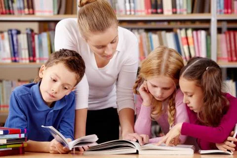 Portrait of pupils and teacher reading interesting book in library Stock Photos