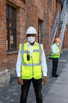 Portrait of qualified worker standing, looking at camera near building site Stock Photos