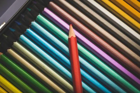 A portrait of a red colored pencil on a stack of other color pencils in a box Stock Photos