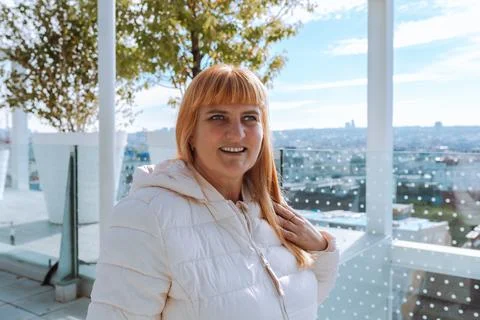 Portrait red-haired middle-aged woman against blurred cityscape background Stock Photos