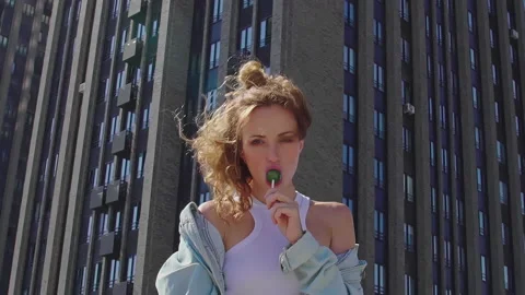 Portrait of Red-Haired model sucks lollipop on rooftop, enjoying view over city Stock-Footage 160559830