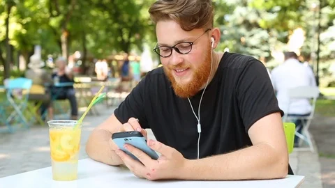 Portrait redhead man with a beard  writes a message in a smartphone Stock Footage 114177771