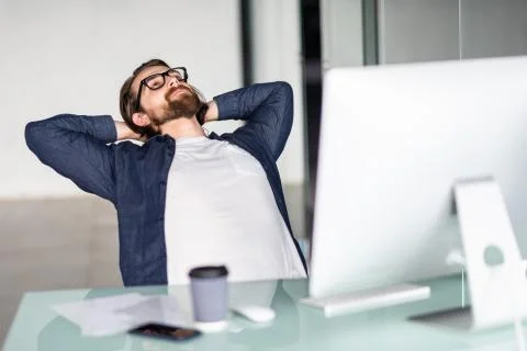Portrait of a relaxed man in front of a computer in office Stock Photos
