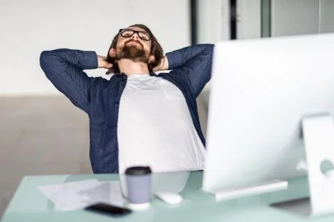 Portrait of a relaxed man in front of a computer in office Stock Photos
