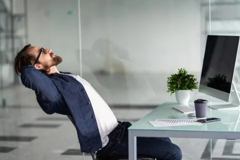 Portrait of a relaxed man in front of a computer in office Stock Photos