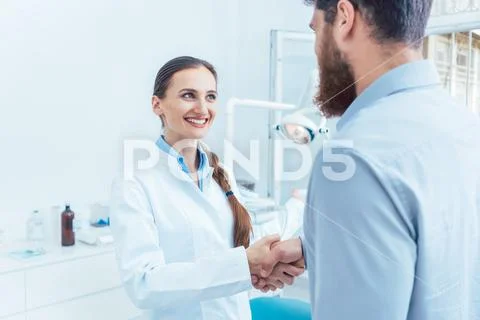 Portrait of a reliable and cheerful dentist shaking the hand of a patient Stock Photos
