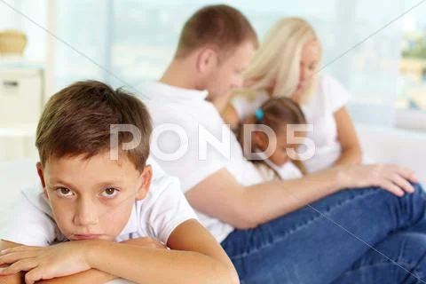 Portrait of sad boy on background of his parents and sister Stock Photos