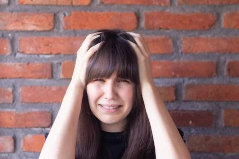 Portrait of a sad brunette woman with bangs wearing a black t-shirt on brick  Stock Photos
