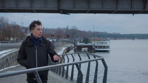 Portrait of a sad man enduring a cold winter day by the city river Stock Footage 311193262