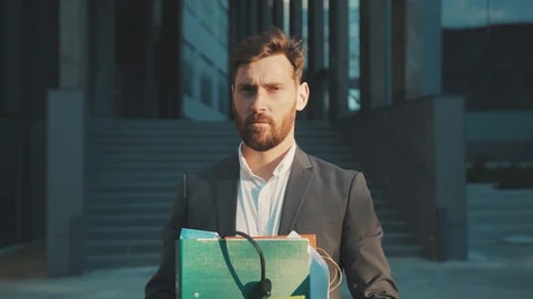 Portrait sad young man stand look at camera with box of personal stuff at Video stock 129463586
