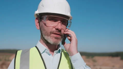 Portrait sand quarry worker engineer talks instructing builders with cellphone Stock Footage 156458015