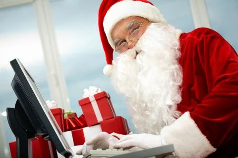 Portrait of santa claus in front of computer monitor looking at camera Stock Photos
