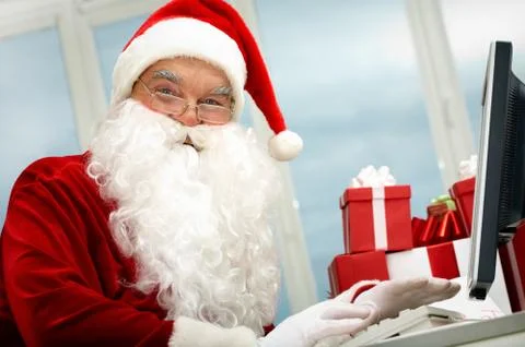 Portrait of santa claus in front of computer monitor looking at camera Stock Photos