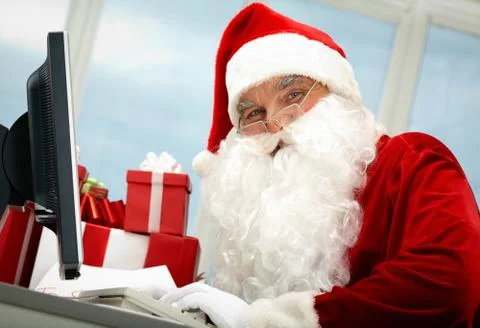 Portrait of santa claus in front of computer monitor looking at camera Stock Photos