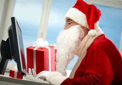 Portrait of santa claus in front of computer monitor with gifts Stock-Fotos