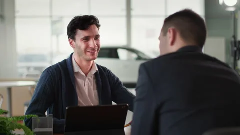 Portrait of a satisfied male customer talking to a auto dealer about a buying Vídeo Stock 201201638