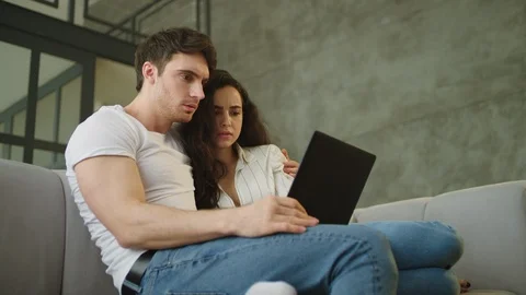 Portrait of scared couple looking computer screen at sofa in slow motion. Stock Footage 119881490