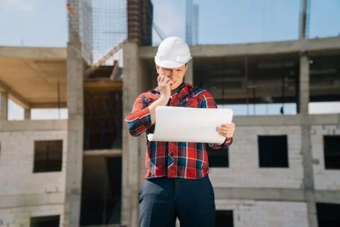 Portrait of a scared man in a white protective helmet with paper on a background Stock Photos