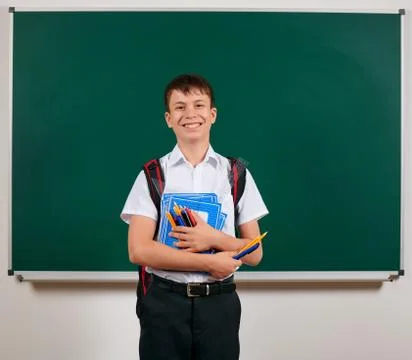 Portrait of a school boy posing with backpack and school supplies, blackboard Stock Photos