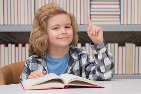 Portrait of school boy reading book in library. Kids development, learn to read Fotos de archivo