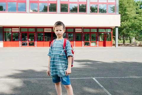 Portrait of a schoolboy with a backpack on his back standing against the Stock Photos