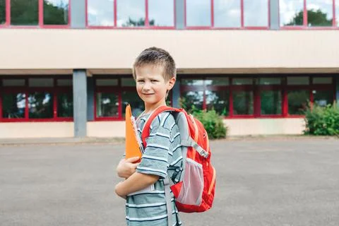 Portrait of a schoolboy boy with a backpack on his back and textbooks in his Stock Photos