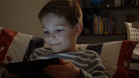 Portrait of schoolboy playing with tablet in bed in the night Video stock 134555152
