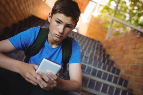 Portrait of schoolboy using mobile phone on staircase Foto stock