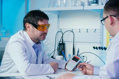 Portrait of a scientist working in the lab examines a test tube with liquid. Stock Photos
