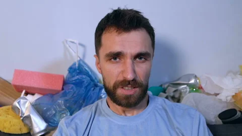 Portrait of screaming man sitting on the couch surrounded by trash and garbage.  Stock Footage 120008723
