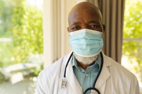 Portrait of senior african american male doctor in face mask and lab coat Stock Photos