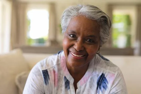 Portrait of senior african american woman sitting on sofa looking at camera and Stock Photos