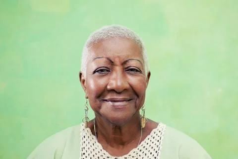 Portrait of senior black woman smiling at camera on green background Stock Photos