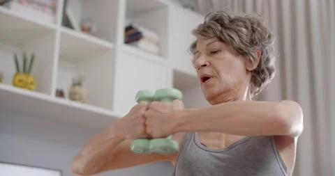 Portrait of senior lady doing energizing dumbbell exercises at home, fitness Stock Footage 231797994