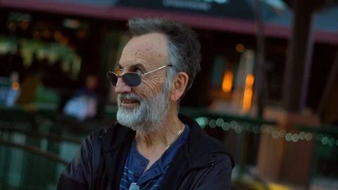 Portrait of a senior man looking at the camera waiting at a commercial mall Stock Footage 107942560