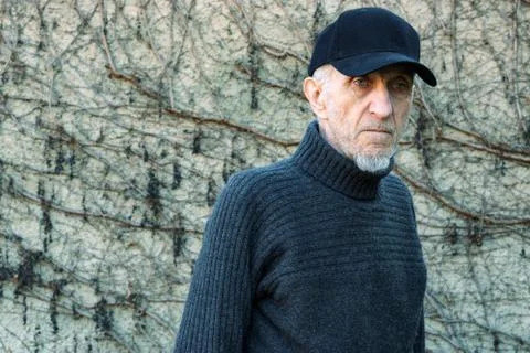 Portrait of senior man with is posing cap in front of a wall Stock Photos
