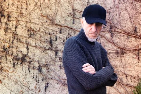 Portrait of senior man with is posing cap in front of a wall Stock Photos