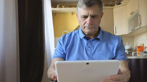 Portrait of a senior man types a tablet PC at home Stock Footage 59697003