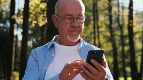 Portrait of senior man using mobile phone, holding device, texting, surfing Video stock 97791541