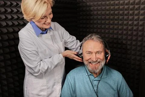 Portrait senior man while hearing check-up with audiologist at soundproof aud Foto stock