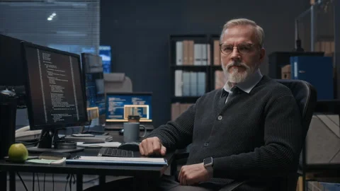Portrait of Senior Programmer at Desk with Code on Computer Screen at Night Video stock 324028144