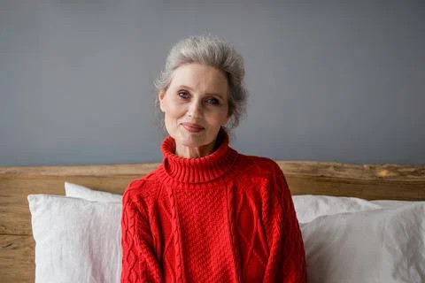 Portrait of senior woman in a red sweater at room. Stock Photos