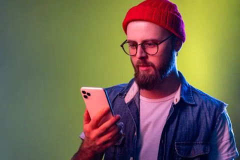 Portrait of serious assertive hipster man typing on smartphone, betting, using Stock Photos