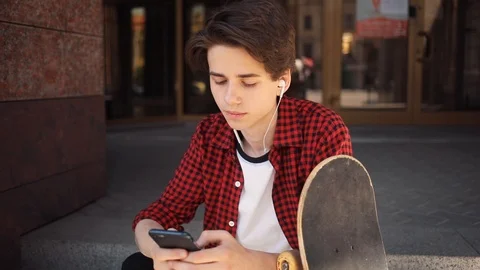 Portrait serious boy look at camera using mobile phone with headphones keeps Stock Footage 92051709