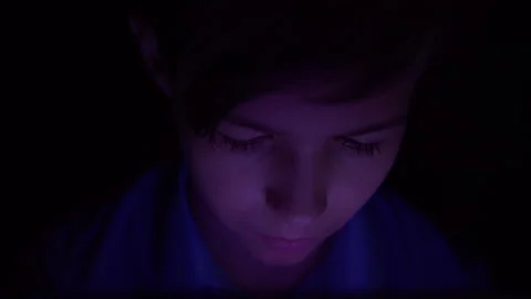 Portrait of a serious boy looking at tablet in dark night, Thoughtfully doing Stock Footage 135274115