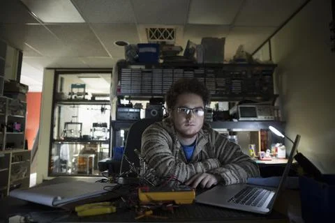Portrait serious computer programmer working at laptop in dark office Stock Photos