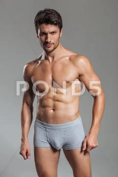 Portrait of a serious handsome muscular man in underwear standing Stock Photos