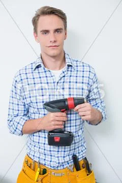 Portrait of a serious handsome young handyman holding drill Stock Photos